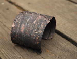 Copper bracelet covered with flaky black firescale.